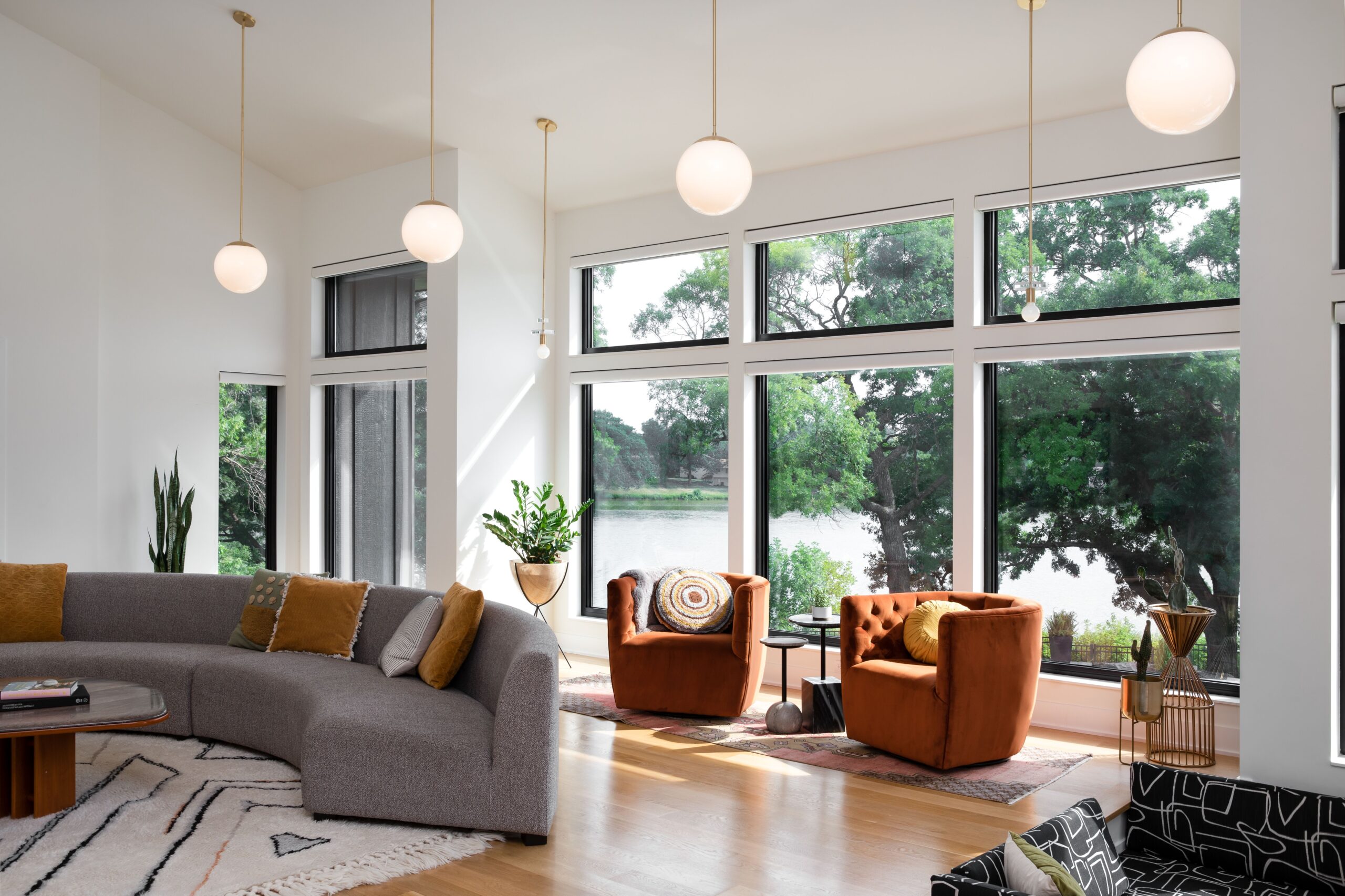 Living room with chairs and arched couch and pendant lighting with large glass windows. Marvin replacement windows available at Consolidated Builders Supply.